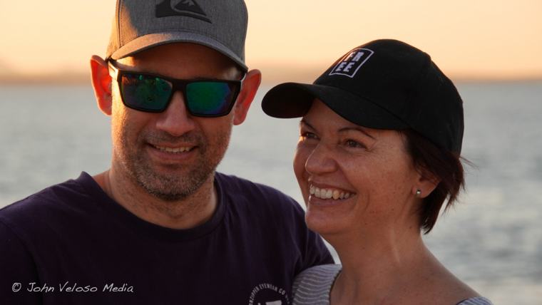 Couple smiling by the water at sunset